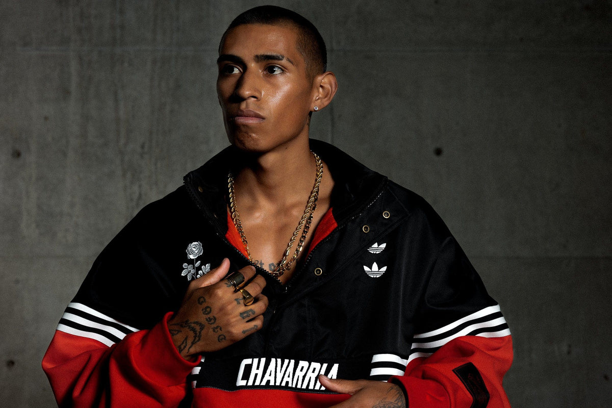 Willy Chavarria Person wearing a black and red jacket with 'CHAVARRIA' branding against a dark background