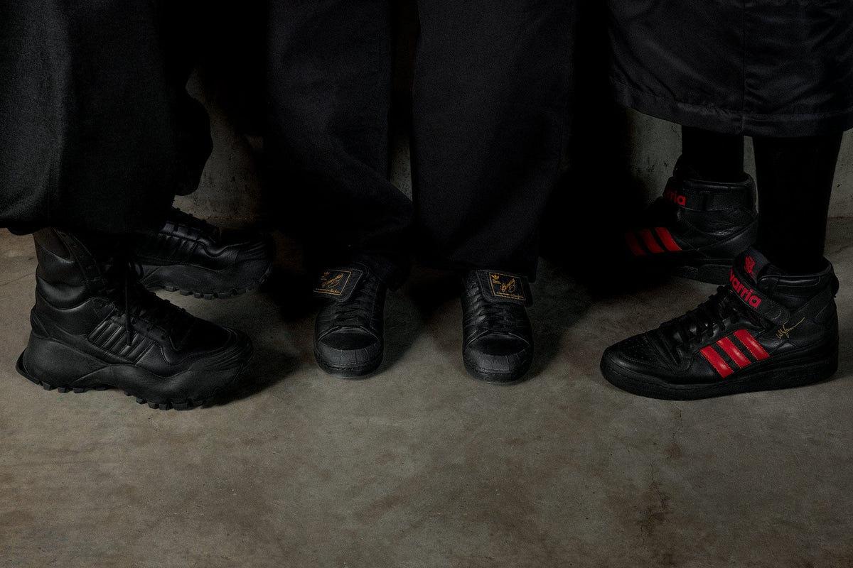 Willy Chavarria Adidas trainers on a concrete floor, with one pair featuring red accents.