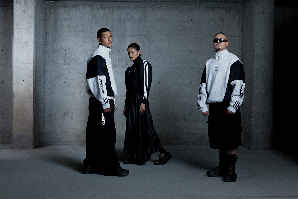 Willy Charravia Adidas. Three people wearing matching black and white outfits in a concrete room.