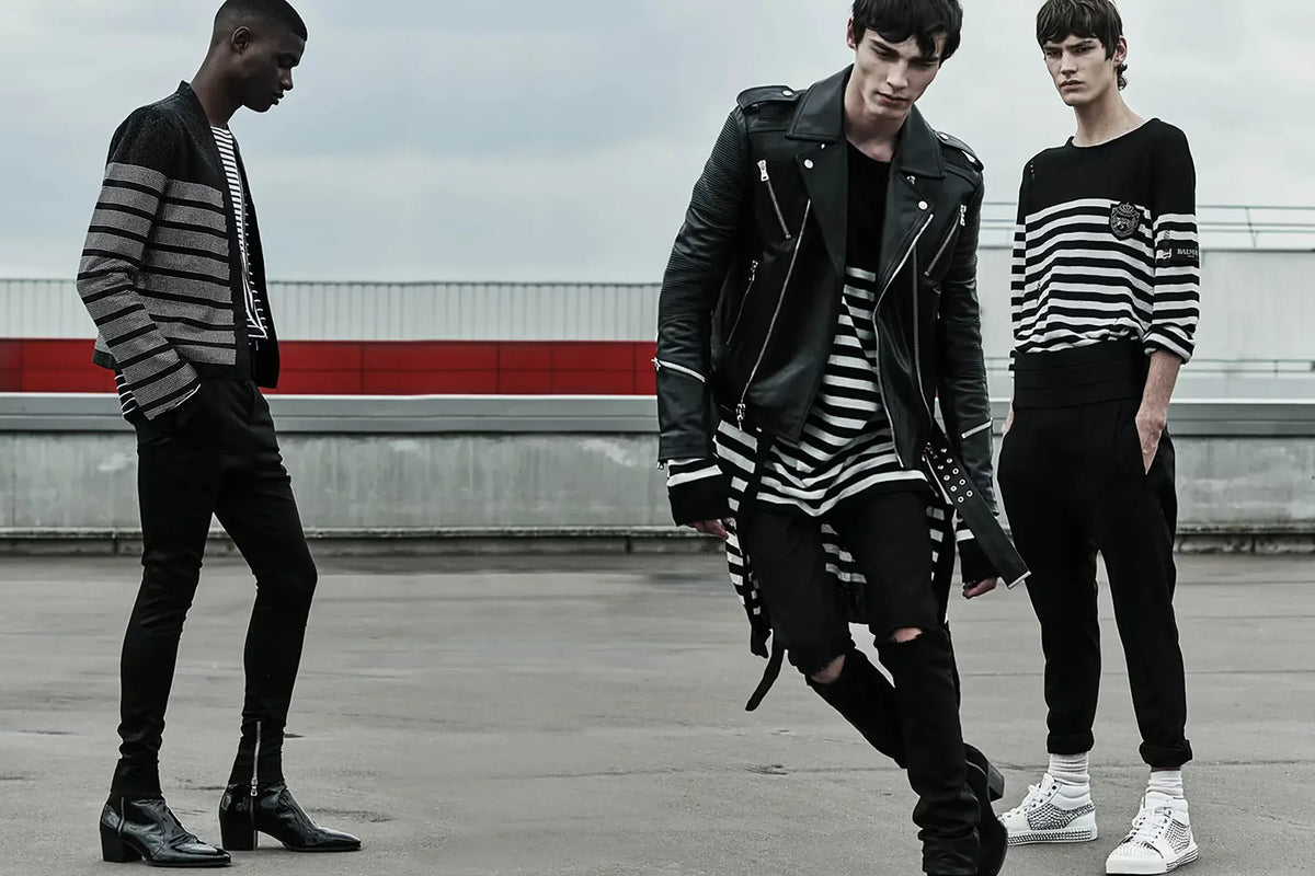Balmain clothing for men. Three individuals wearing black and white striped outfits on a rooftop.