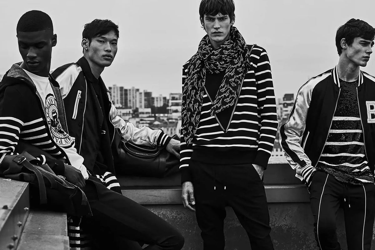 Balmain clothing for men. Four men in stylish outfits with a cityscape background
