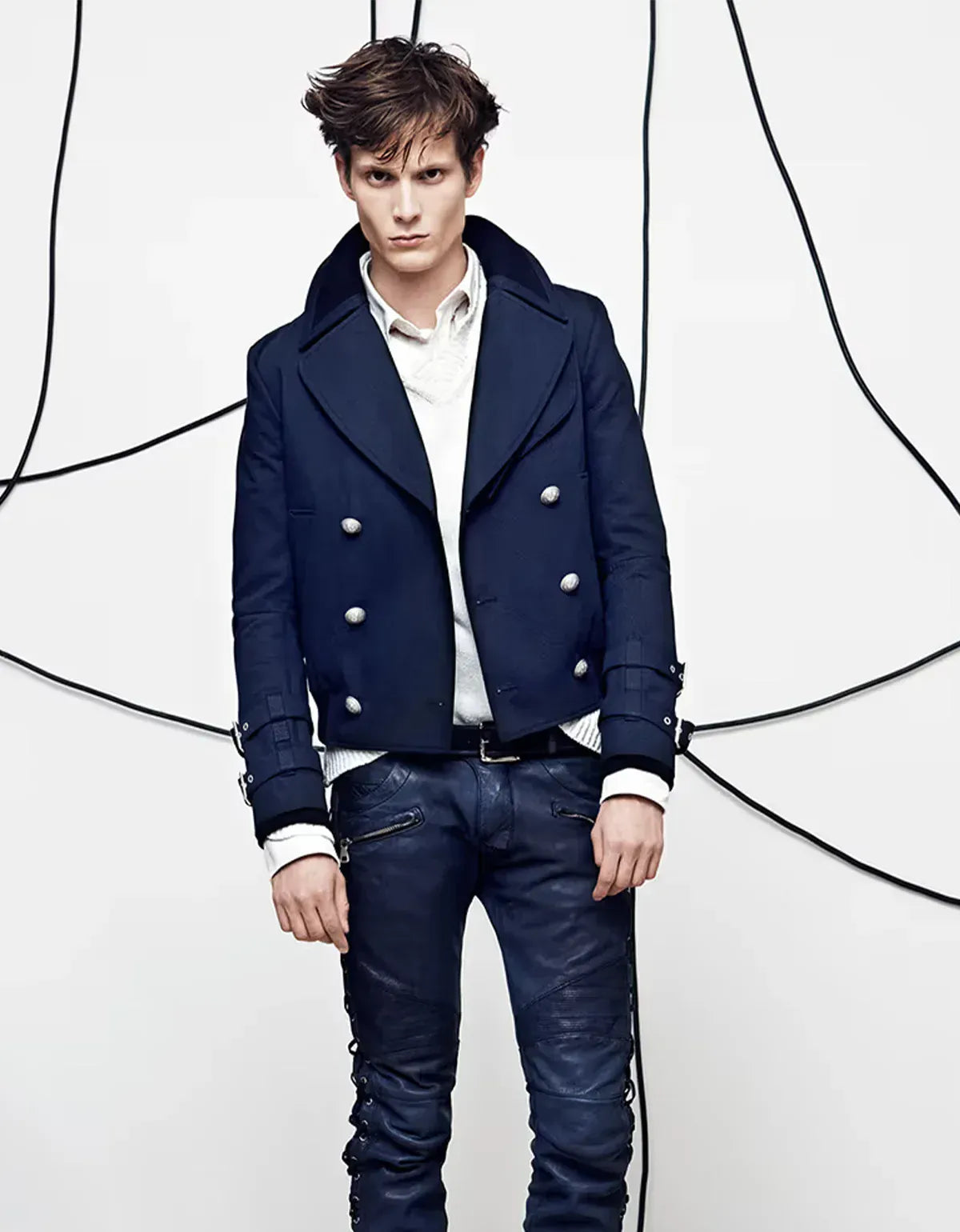 Balmain clothing for men. Man wearing a navy blue jacket with white buttons on a white background