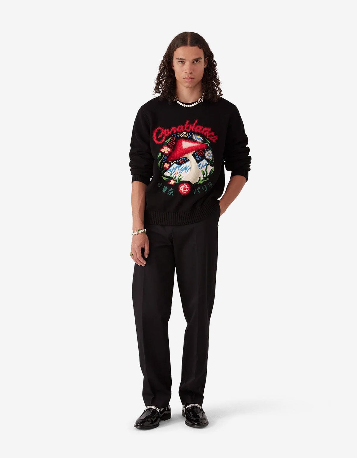 Casablanca Black Chino Trousers MPF25-TR-321-01. Model wearing a black sweater with colourful designs and black pants