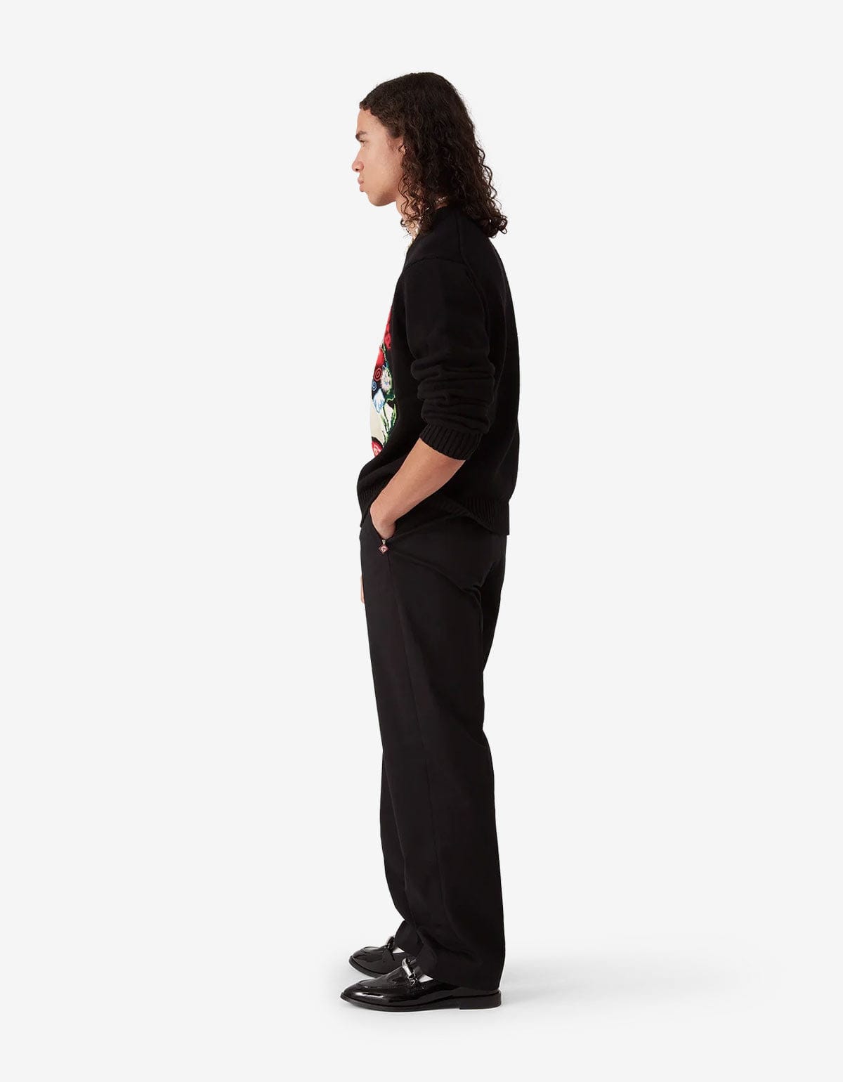 Casablanca Black Chino Trousers MPF25-TR-321-01. Model wearing a black sweater with colourful designs and black pants