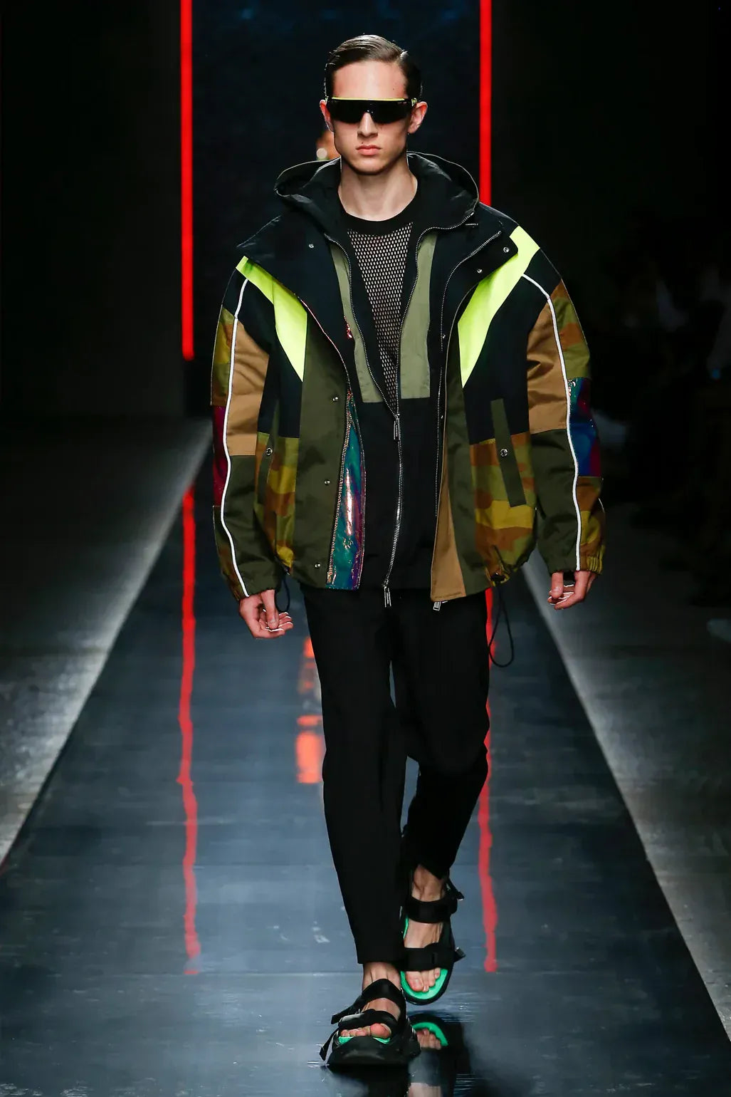 DSquared2 clothing for men. Model walking on a runway wearing a colorful jacket with reflective elements.