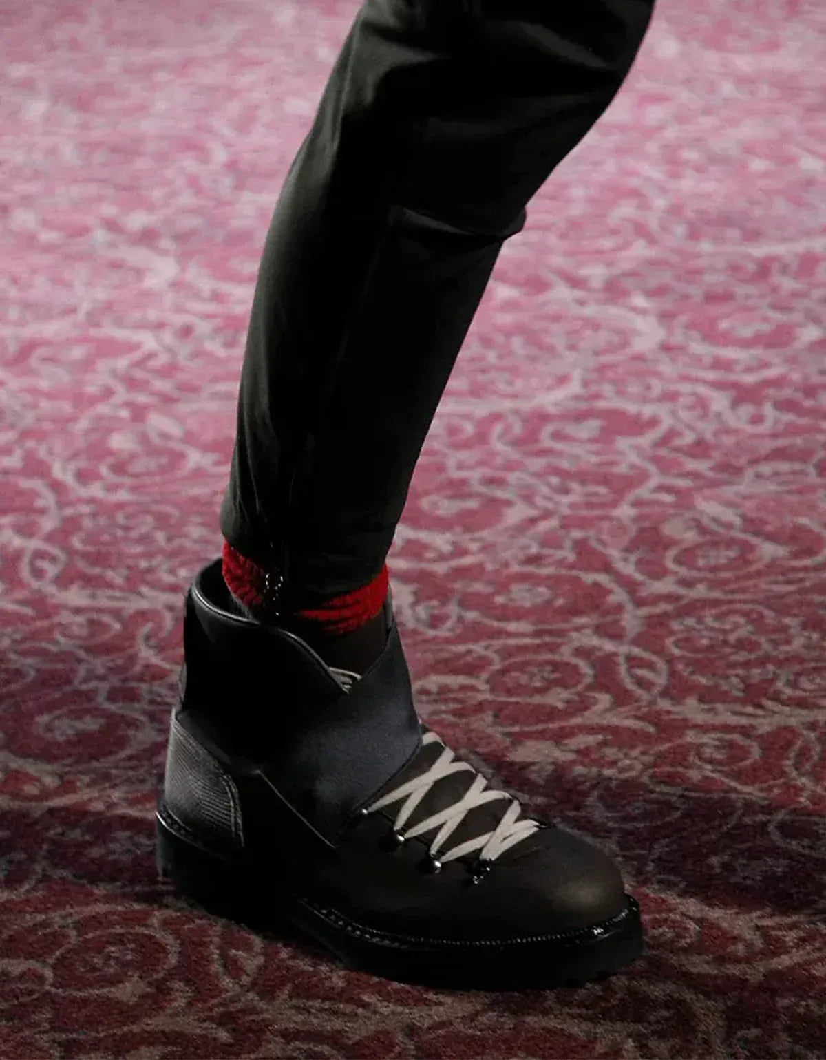 Lanvin shoes for men. Black leather boot worn on a patterned carpet