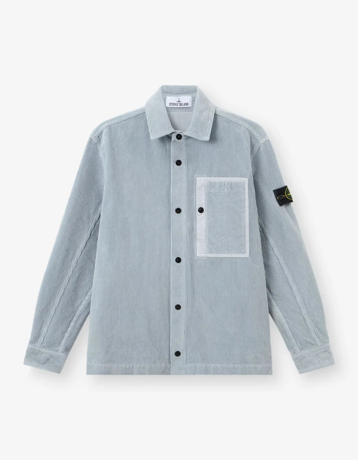 A light blue-gray Stone Island corduroy jacket, featuring the signature black and yellow compass patch on the left sleeve, set against a clean off-white background.