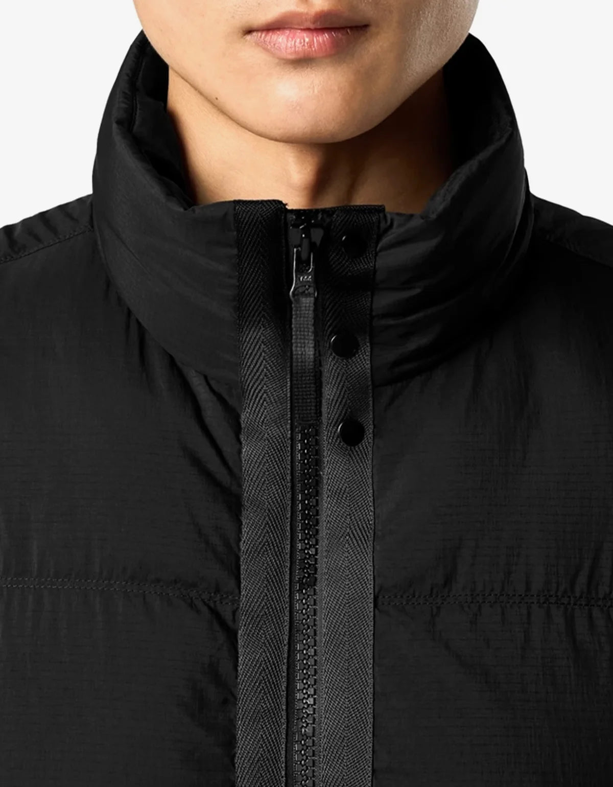 Close-up of a person wearing a black puffer jacket with a high stand-up collar and front zipper.