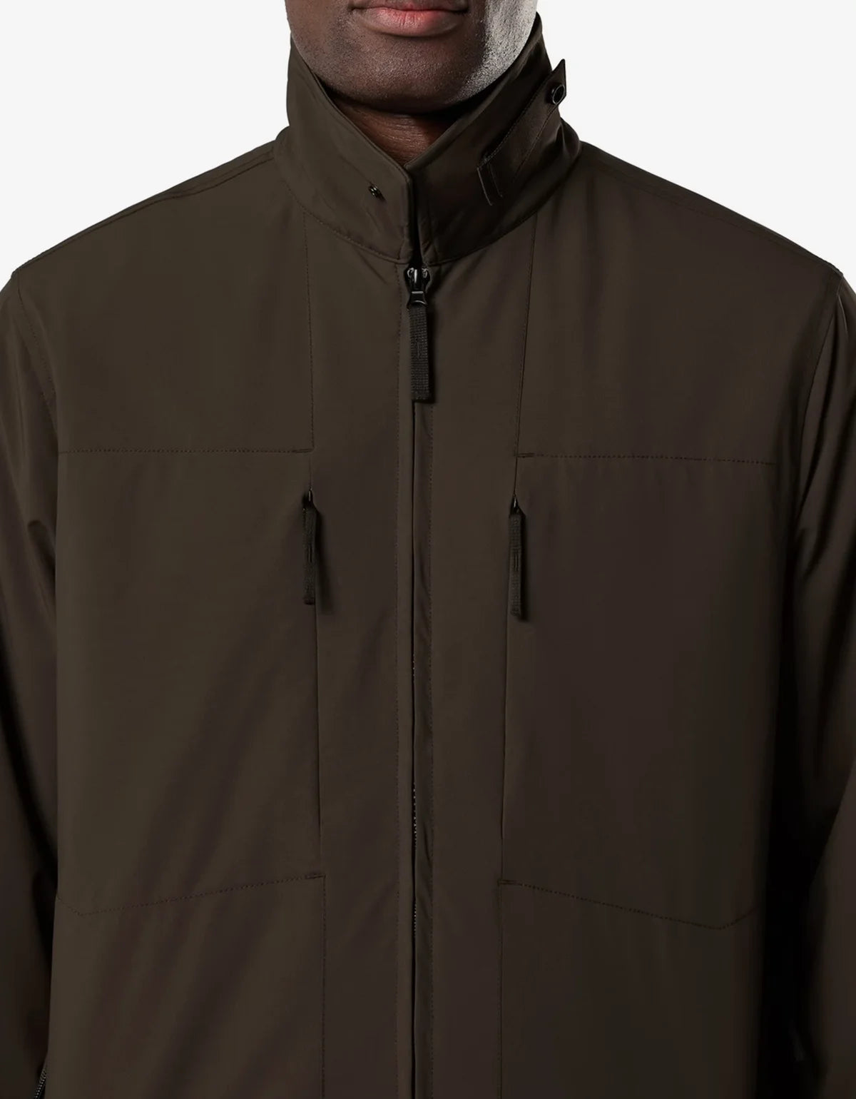 Close-up of a person wearing a dark brown zip-front jacket with a stand collar and two vertical zip chest pockets, shown against a plain light background.
