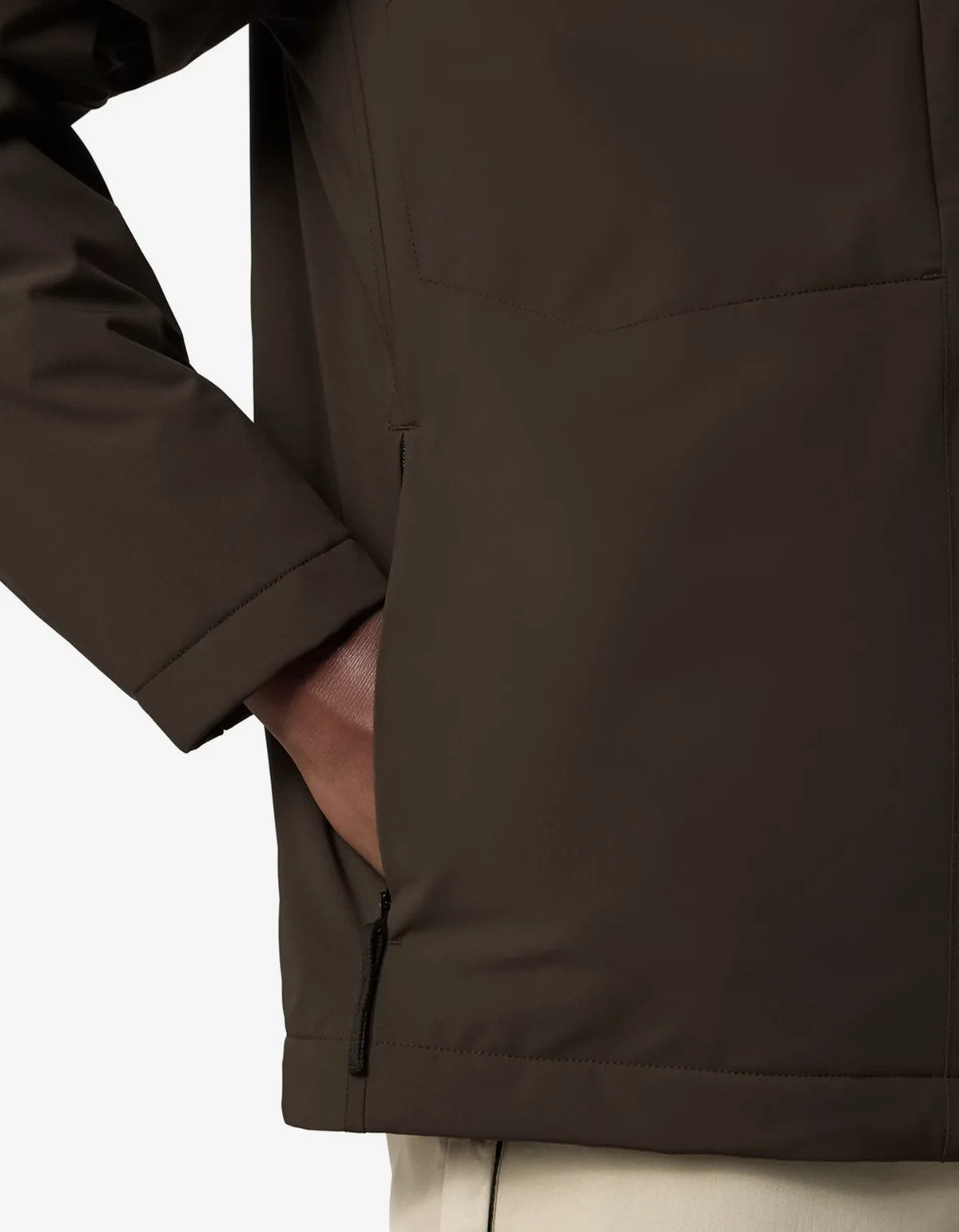 Close-up of a dark brown jacket with a side zipper and pocket, worn by a model with a hand in the pocket, against a white background.