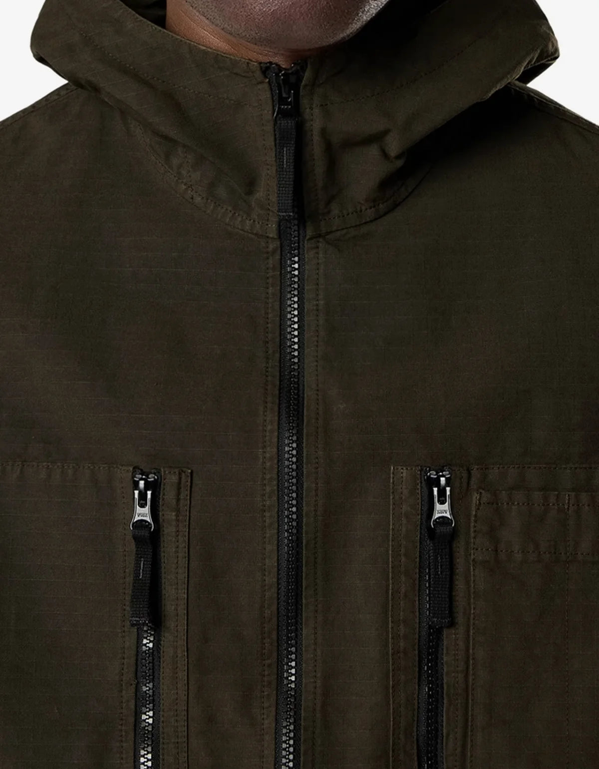Close-up of a hooded jacket in dark olive green, showing the front zipper, hood, and two vertical zippered chest pockets.