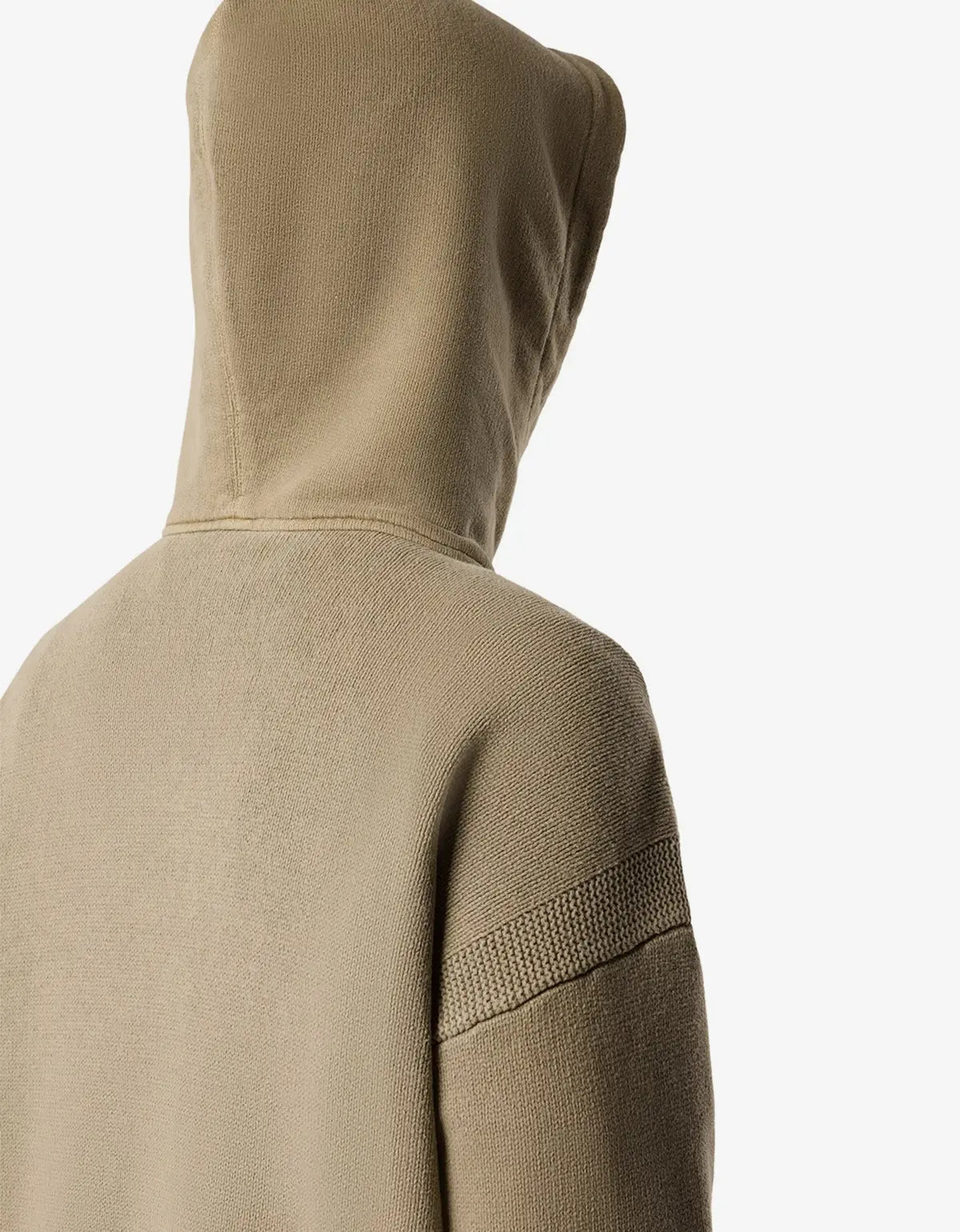 Close-up back view of a beige hooded sweatshirt on a model, showing the textured fabric and a ribbed knit detail on the upper sleeve against a plain white background.