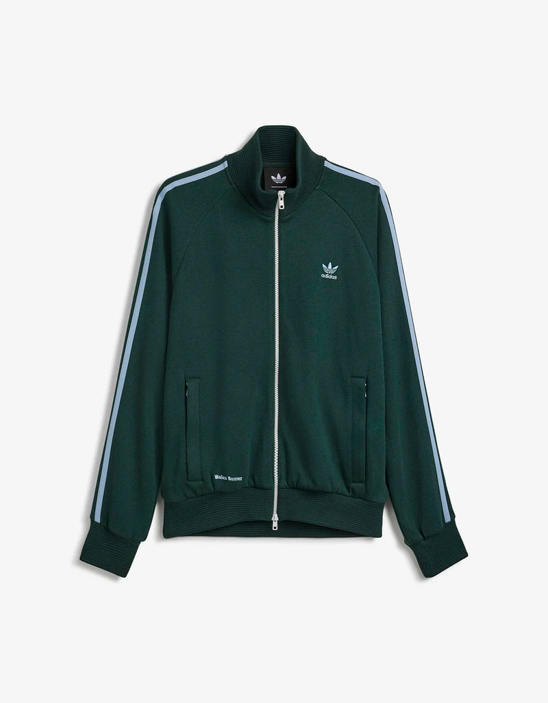 A dark green Adidas track jacket with light blue stripes down the sleeves and a white embroidered trefoil logo on the chest, displayed against a light gray background.