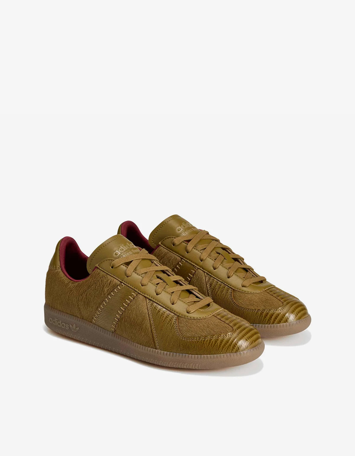 A pair of low-top sneakers in a textured olive-brown leather, featuring matching laces, a gum sole, and a contrasting dark red interior lining, shown on a light gray background.