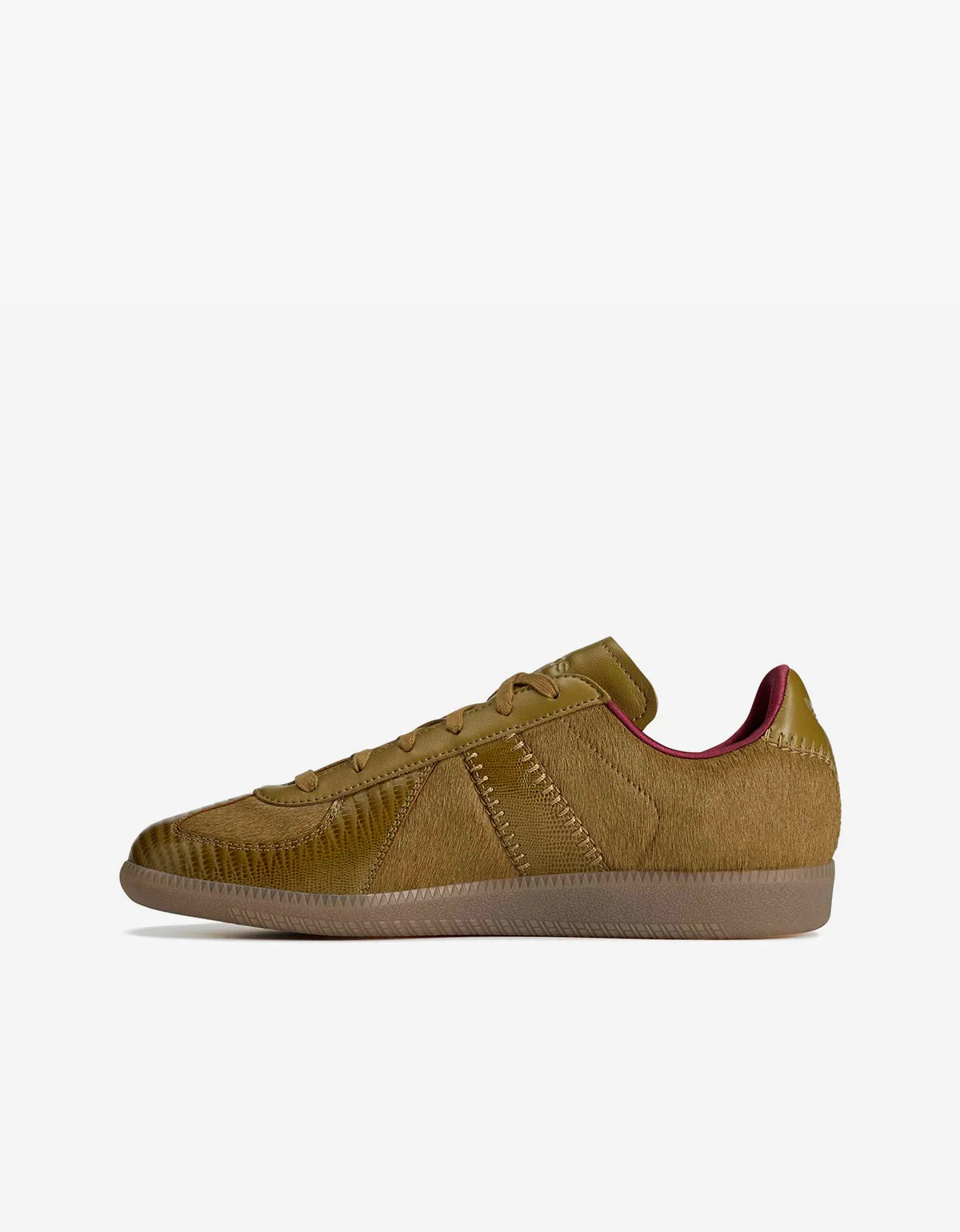 A single low-top sneaker in a textured olive green and brown colorway, featuring a suede-like finish, matching laces, and a gum sole, shown from a side profile on a light gray background.