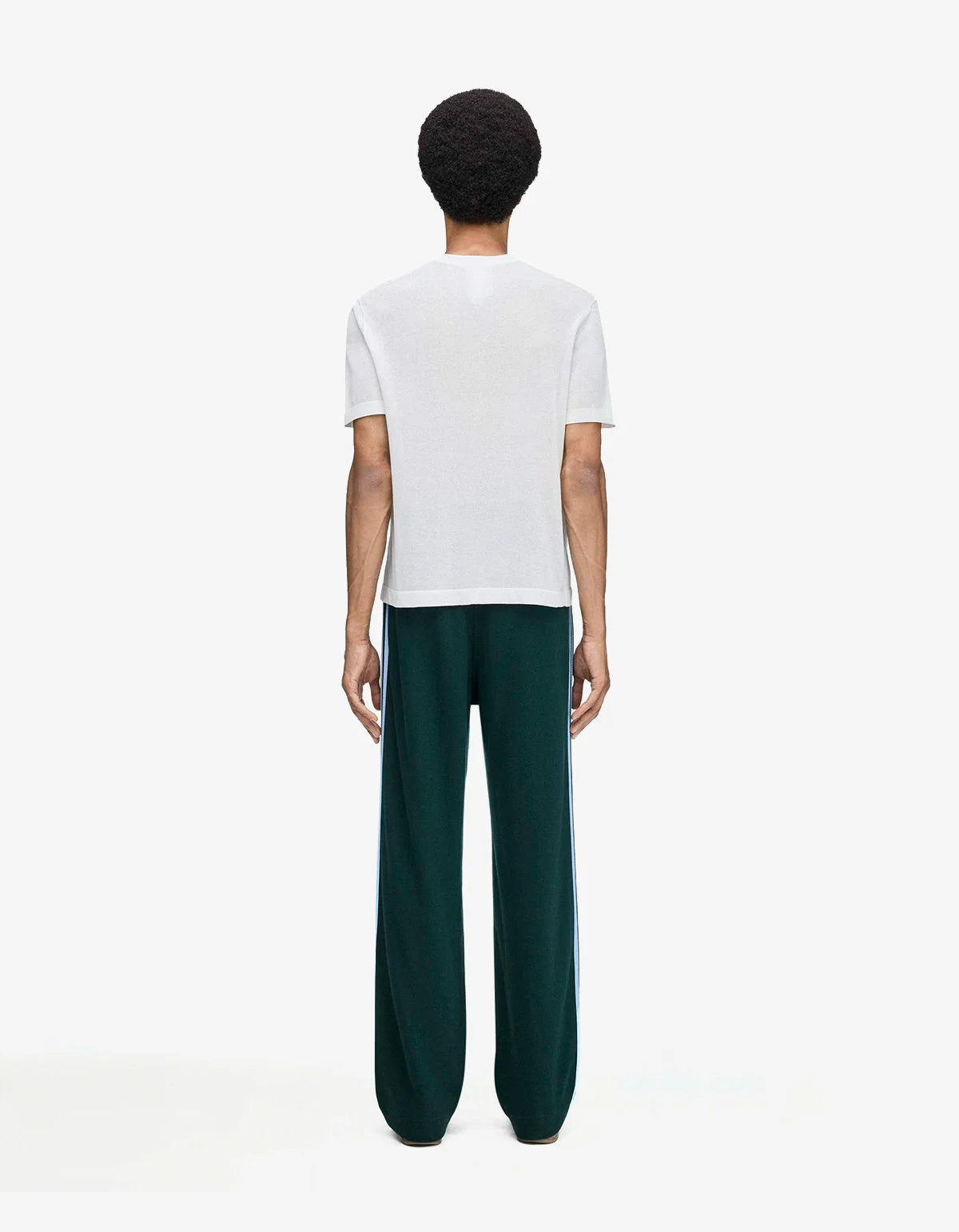 A model shown from the back wearing a white short-sleeve t-shirt and dark green wide-leg trousers with white side stripes, set against a plain white studio background.