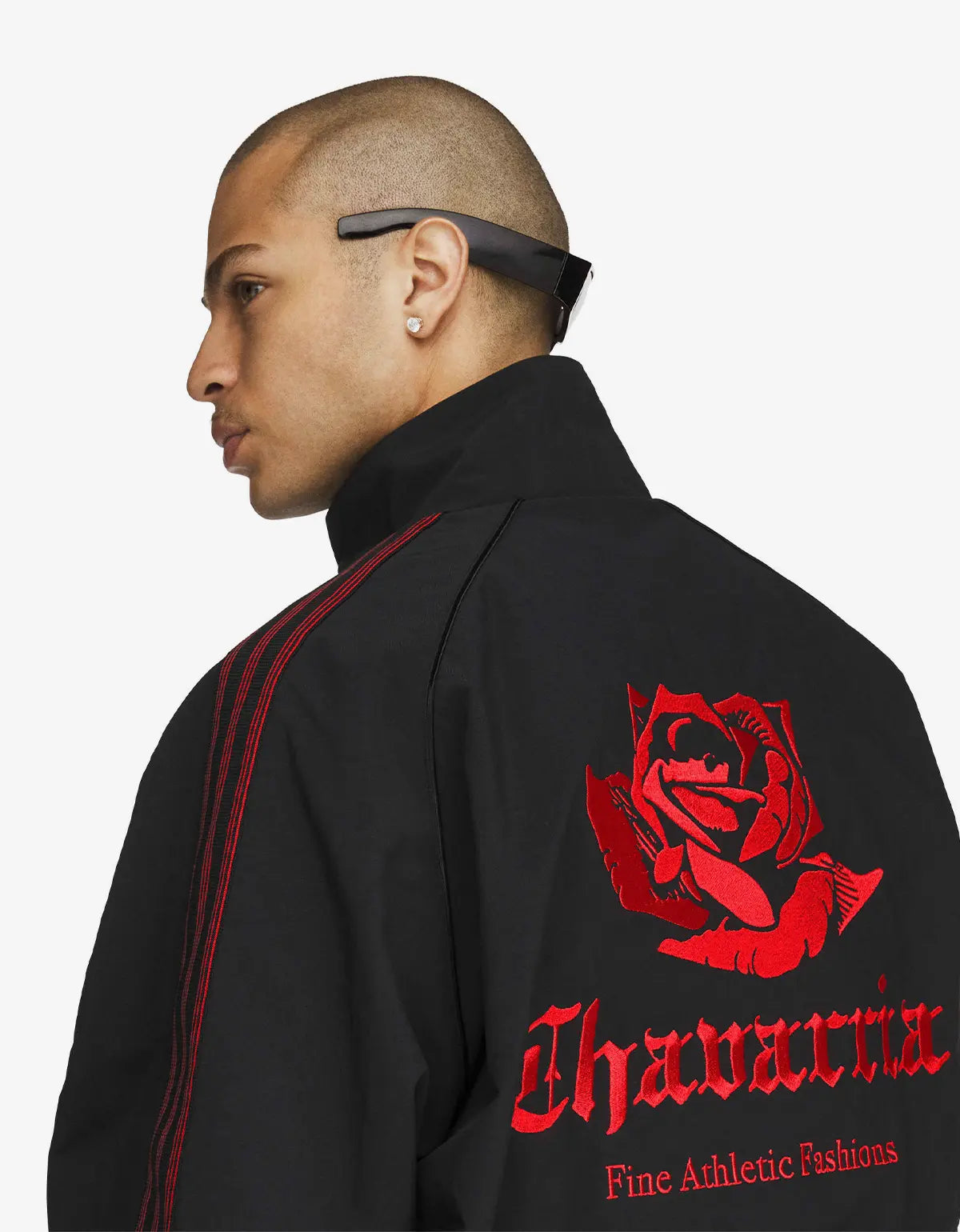 A man shown in profile wearing a black athletic jacket with red stripe detailing on the shoulder and a large red rose graphic with the brand name 'Chavarria' printed in red on the back, against a light gray studio background.
